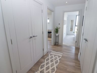 A hallway with wooden floor cabinets and a patterned rug with doors leading to rooms at The Links 40 An apartment with spectacular sea views in Porthcawl