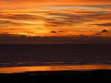 A beach and sea with an orange sunset sky at The Links 40 An apartment with spectacular sea views Porthcawl