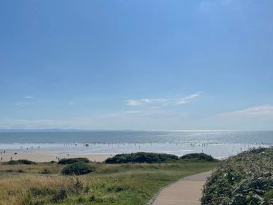 A pathway leading to a beach with people near the water at The Links 40. An apartment with spectacular sea views in Porthcawl
