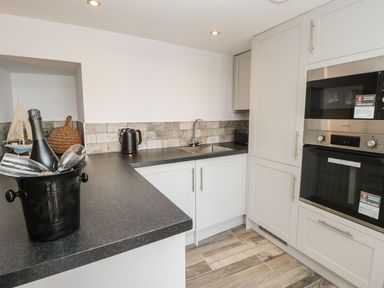 A kitchen with black countertop a sink built in oven microwave and cabinets at The Beach Apartment in South Shields