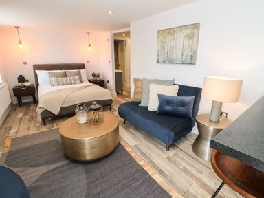 A bedroom with a bed couch coffee table side tables lamps and wall art at The Beach Apartment in South Shields