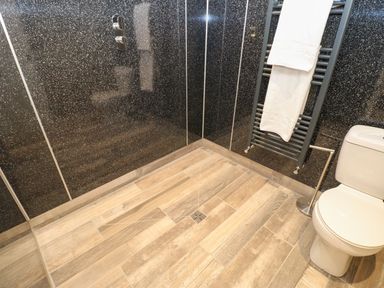 A bathroom with a shower area a towel rack with towels and a toilet at The Beach Apartment in South Shields