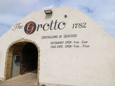 Arched entrance to a building with writing about a seafood restaurant and cave cafe at The Beach Apartment in South Shields