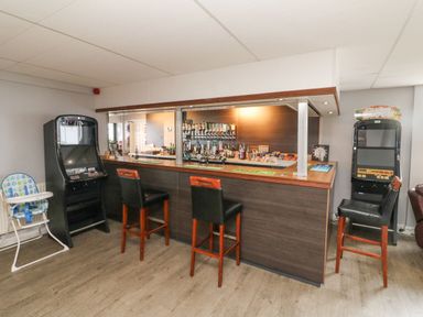 A bar area with stools two gaming machines and a high chair at Atlantic Escape in Widemouth Bay