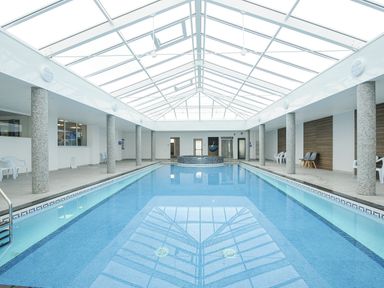 An indoor swimming pool with tiled columns around the perimeter under a glass roof at Atlantic Escape in Widemouth Bay