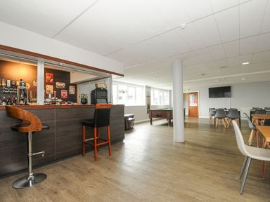 A room with a bar counter and stools a pool table chairs tables a television and windows at Atlantic Escape in Widemouth Bay