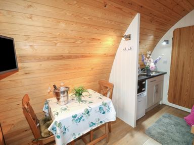 A small dining area with a table and two chairs next to a kitchenette with a sink and flowers at Chantelles in Holbeach