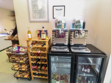 A beverage area with two beer dispensers on top of glass-door refrigerators and a wooden wine rack with bottles at Chantelles in Holbeach