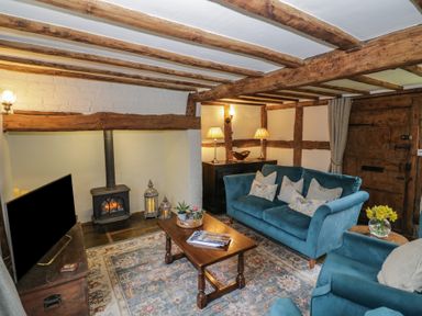 A living room with blue sofas wooden beams a coffee table a fireplace and a television at Church View in Welford-On-Avon