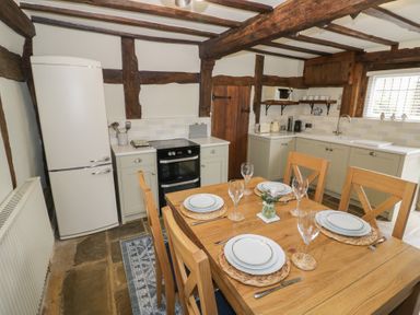 A kitchen with wooden dining table set for four and appliances at Church View in Welford-On-Avon