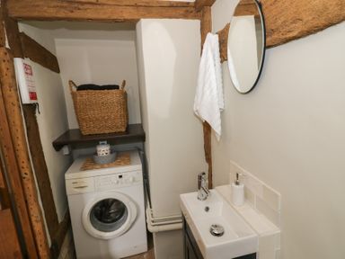 A utility room with a washing machine sink mirror and basket at Church View in Welford-On-Avon