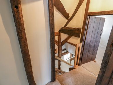 A staircase with wooden beams and a wooden door at the top at Church View in Welford-On-Avon