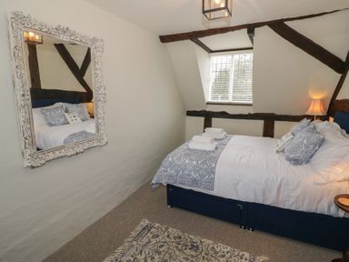 A bedroom with a double bed and pillows next to a window with blinds at Church View in Welford-On-Avon