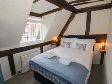 A bedroom with a bed folded towels and pillows under a window at Church View in Welford-On-Avon