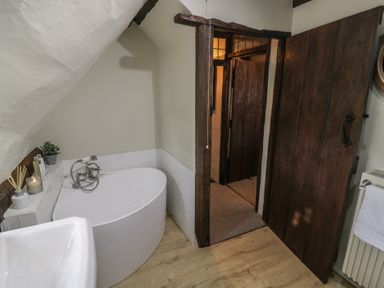 A bathroom with a bathtub sink wooden door and towel rail at Church View in Welford-On-Avon