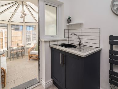 A kitchen area with a sink and cabinets at Driftwood in Rhyl