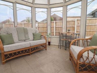 A conservatory with a sofa and a table at Driftwood in Rhyl