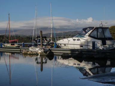 A dock with boats and mountains visible near the water at Highfield Cottage in Windermere
