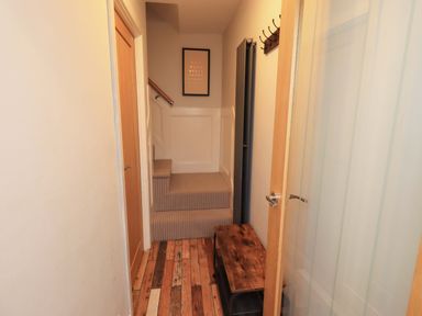 A hallway with stairs and a bench at Highfield Cottage in Windermere