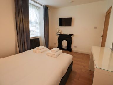 A bedroom with a bed and television at Highfield Cottage in Windermere
