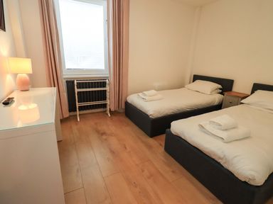 A bedroom with two beds and a window at Highfield Cottage in Windermere
