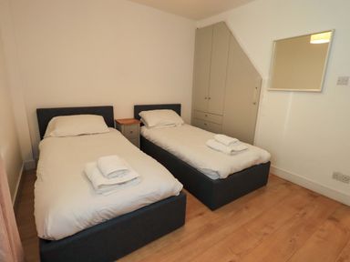 A bedroom with two single beds and storage at Highfield Cottage in Windermere