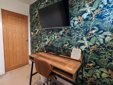 An office with a desk, chair, and television at Highfield Cottage in Windermere