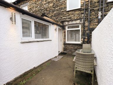 An outdoor area with a table and chairs at Highfield Cottage in Windermere
