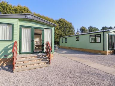 Two green mobile homes on gravel with wooden steps leading to a glass door at Lodge 1 in Silverdale