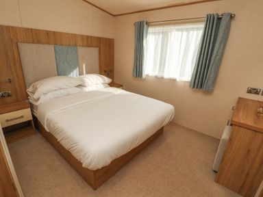 A bedroom with a bed and two nightstands next to a window with curtains at Lodge 1 in Silverdale