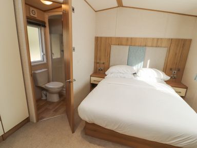 A bedroom with a bed and an open door showing a bathroom with a toilet at Lodge 1 in Silverdale