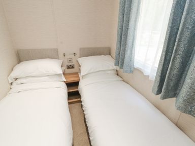 A small bedroom with two single beds separated by a wooden nightstand at Lodge 1 in Silverdale