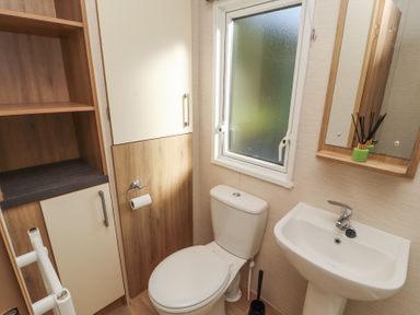 A bathroom with a toilet sink mirror window storage cabinets and a toilet brush at Lodge 1 Silverdale