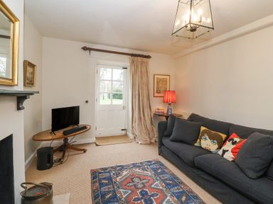 A living room with a dark sofa and patterned rug near a door at Little Lemhill Farm Cottage in Lechlade-On-Thames