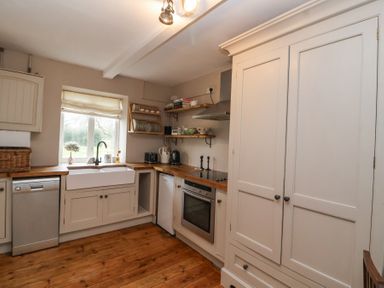 A kitchen with wooden floor cabinets dishwasher oven and shelves at Little Lemhill Farm Cottage Lechlade-On-Thames