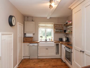 A kitchen with a sink under a window and wooden countertops at Little Lemhill Farm Cottage in Lechlade-On-Thames