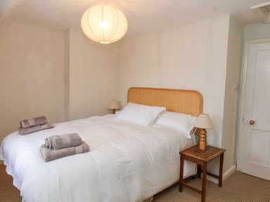 A bedroom with a double bed two bedside tables lamps and folded towels on the bed at Little Lemhill Farm Cottage in Lechlade-On-Thames