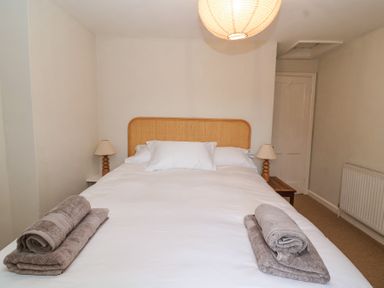 A bedroom with a double bed white linens folded towels bedside tables with lamps and a ceiling light at Little Lemhill Farm Cottage in Lechlade-On-Thames