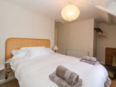 A bedroom with a double bed with white linens and folded towels on top at Little Lemhill Farm Cottage in Lechlade-On-Thames
