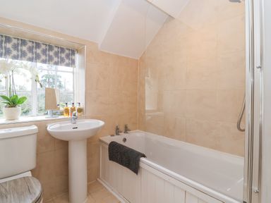 A bathroom with a bathtub white sink toilet and a window with a floral blind at Little Lemhill Farm Cottage in Lechlade-On-Thames