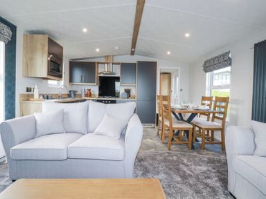 An open plan living area with sofas a dining table with chairs and a kitchen at The Maples No 48 in Hewas Water near Sticker