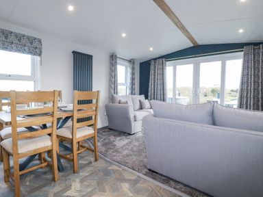 A living room with two sofas and a dining table with four chairs at The Maples No 48 in Hewas Water near Sticker