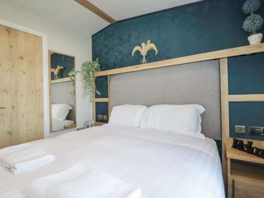 A bedroom with a bed white towels a mirror and plants at The Maples No 48 in Hewas Water near Sticker