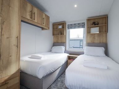 A bedroom with two single beds and wooden cabinets at The Maples No 48 in Hewas Water near Sticker