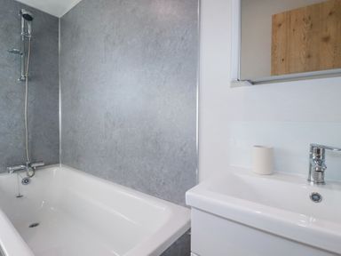 A bathroom with a bathtub and shower next to a sink with a faucet at The Maples No 48 in Hewas Water near Sticker