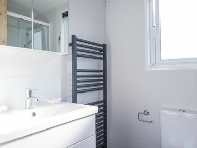 A bathroom with a sink cabinet mirror towel rail toilet and window at The Maples No 48 in Hewas Water near Sticker