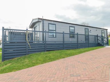 A grey mobile home with a fenced deck and a brick driveway at The Maples No 48 Hewas Water near Sticker