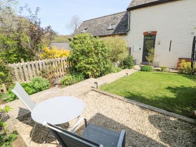 An outdoor patio area with two chairs and a round table beside a lawn and garden at 3 The Barn in Haverfordwest