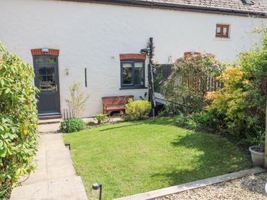 A garden with a grass lawn shrubs and a wooden bench outside a house at 3 The Barn in Haverfordwest