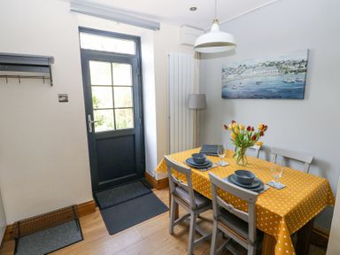 A dining area with a table set for two with a yellow polka dot tablecloth and tulips next to a door at 3 The Barn in Haverfordwest